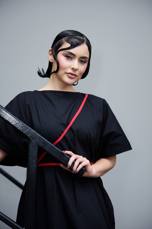A woman wearing a black dress with thin red stripes 